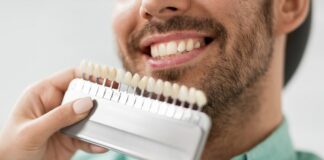 Licówki na zęby - dentystka przykładająca do zębów pacjenta wzornik z licówkami.